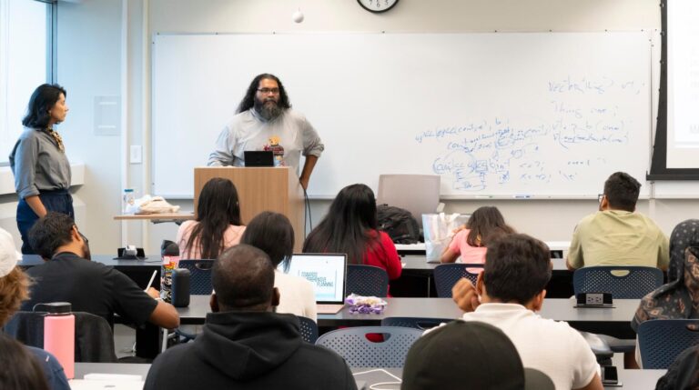 Manny Patole at a lectern in front of a small classroom