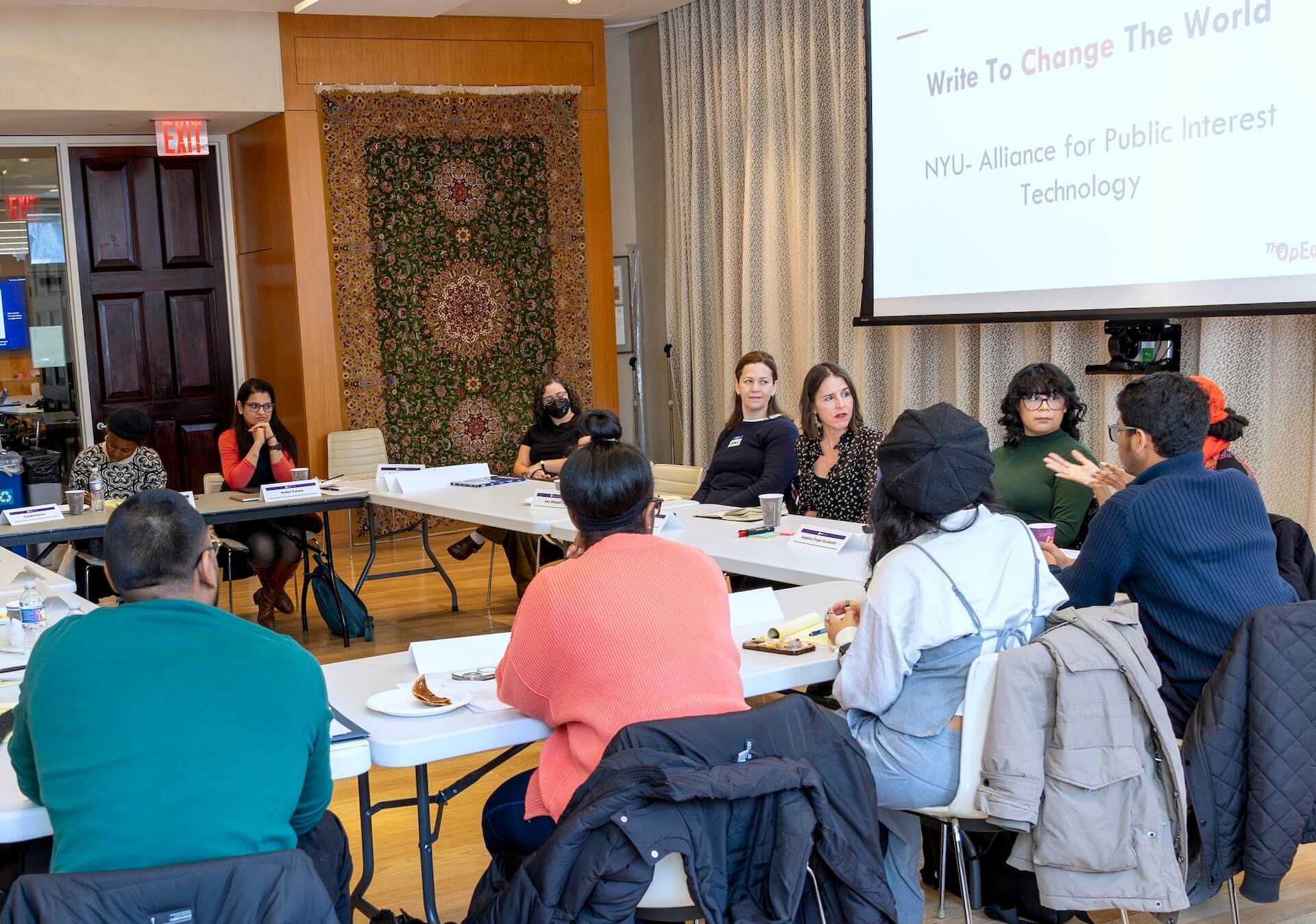 Seated workshop participants. Title on projector screen says "Write to change the world"